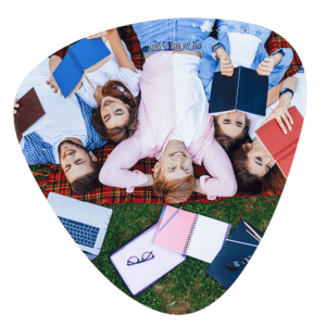 kilka osób lerzących na trawie wraz z noteasmi i komputerem odpoczywające